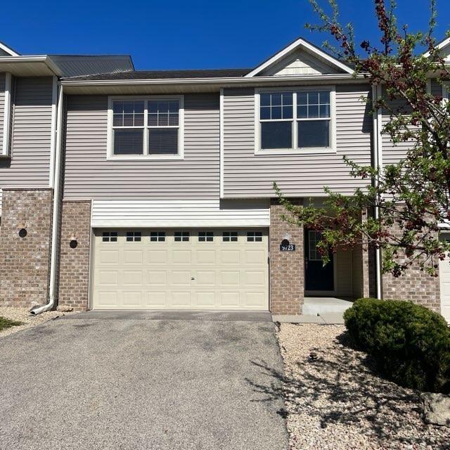 view of front of house featuring brick siding, an attached garage, and aphalt driveway