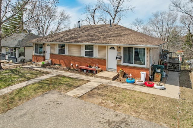 view of front of property with brick siding, a shingled roof, and a front yard