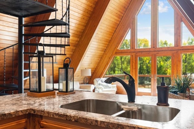 kitchen featuring stone counters, wood walls, french doors, and a sink