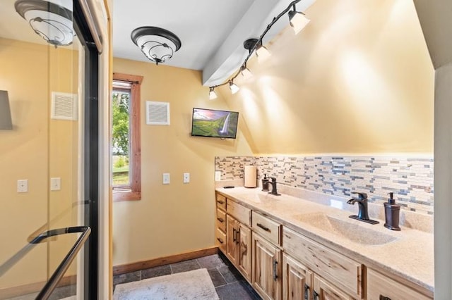 bathroom with baseboards, decorative backsplash, a sink, and visible vents