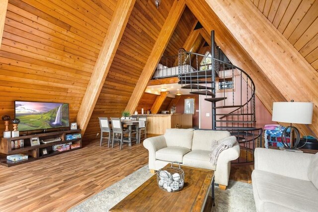 living area featuring wood walls, stairs, wood finished floors, and lofted ceiling with beams