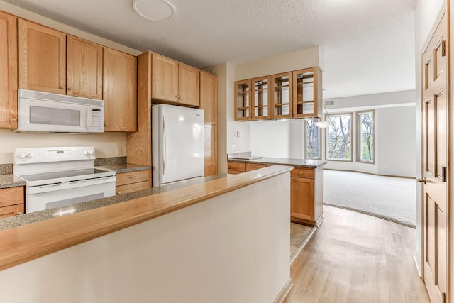 kitchen featuring a peninsula, white appliances, glass insert cabinets, a textured ceiling, and light wood finished floors
