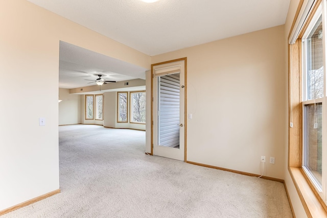 carpeted empty room featuring baseboards and ceiling fan