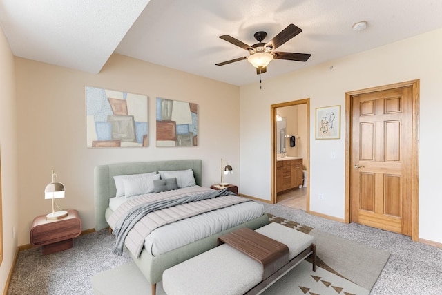 bedroom featuring baseboards, a ceiling fan, ensuite bath, and light colored carpet