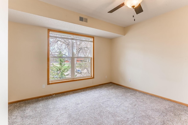 carpeted empty room featuring baseboards, a ceiling fan, and visible vents