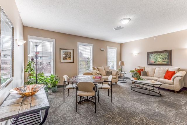 carpeted living room with baseboards, a textured ceiling, and visible vents