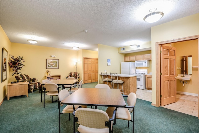 dining space featuring a textured ceiling, baseboards, light tile patterned flooring, and light colored carpet