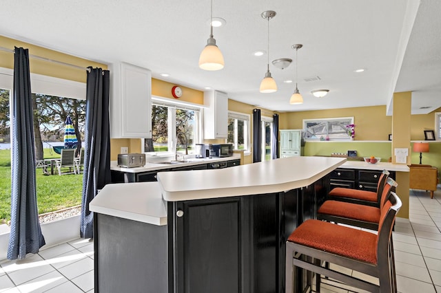 12329 Timber Ln, Maple Grove, MN 55369 - kitchen featuring dark cabinets, light countertops, light tile patterned floors, white cabinets, and decorative light fixtures
