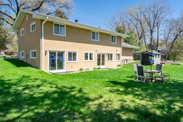 12329 Timber Ln, Maple Grove, MN 55369 - back of house featuring a storage unit, stucco siding, a lawn, and an outbuilding