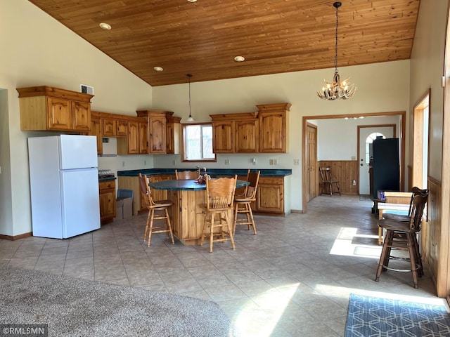 kitchen featuring wood ceiling, a breakfast bar area, freestanding refrigerator, a kitchen island, and dark countertops