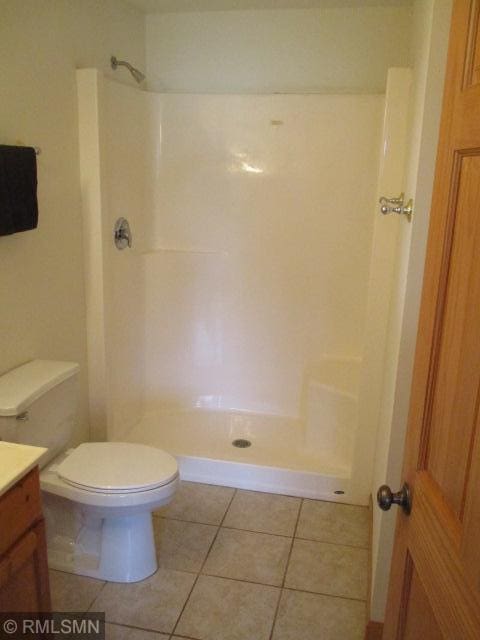 bathroom with tile patterned floors, toilet, walk in shower, and vanity