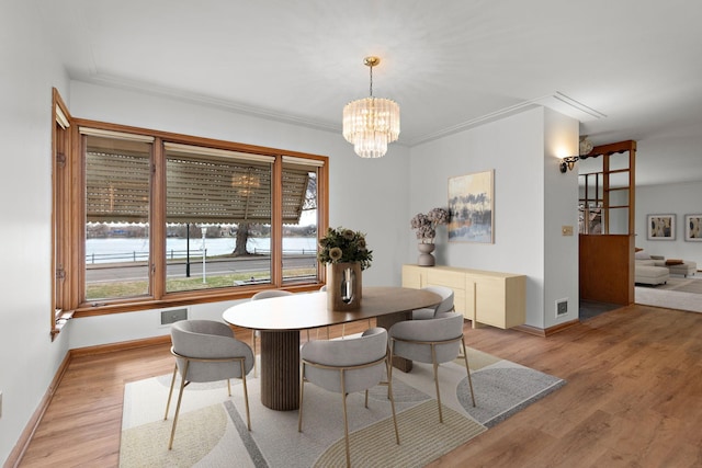dining area with a chandelier, light wood-type flooring, and baseboards