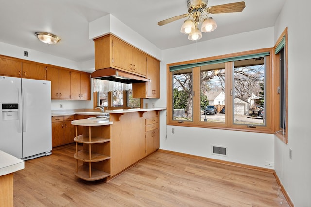 kitchen with white refrigerator with ice dispenser, light wood-style flooring, light countertops, ceiling fan, and a peninsula