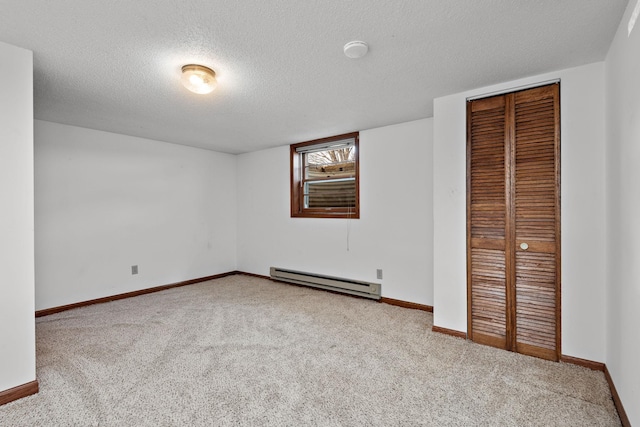 unfurnished bedroom featuring baseboard heating, carpet flooring, a textured ceiling, a closet, and baseboards