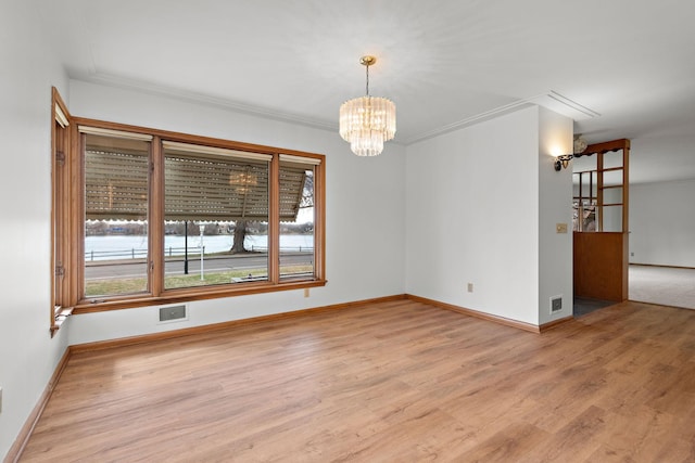 spare room featuring wood finished floors, a chandelier, and baseboards