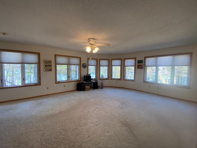 unfurnished living room featuring light carpet, a ceiling fan, baseboards, and a textured ceiling