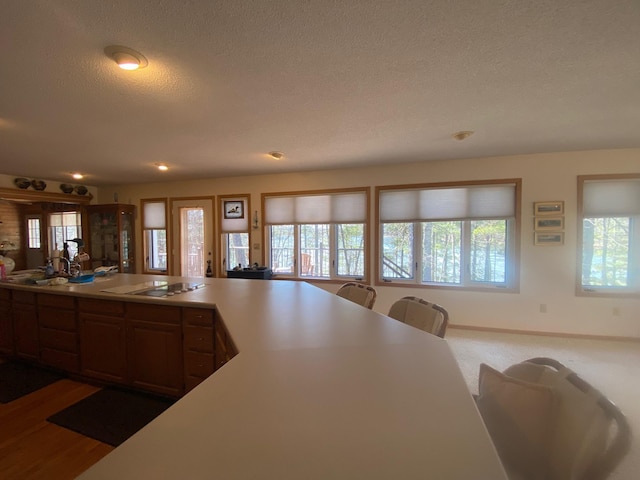 kitchen with a sink, a textured ceiling, recessed lighting, electric stovetop, and light countertops