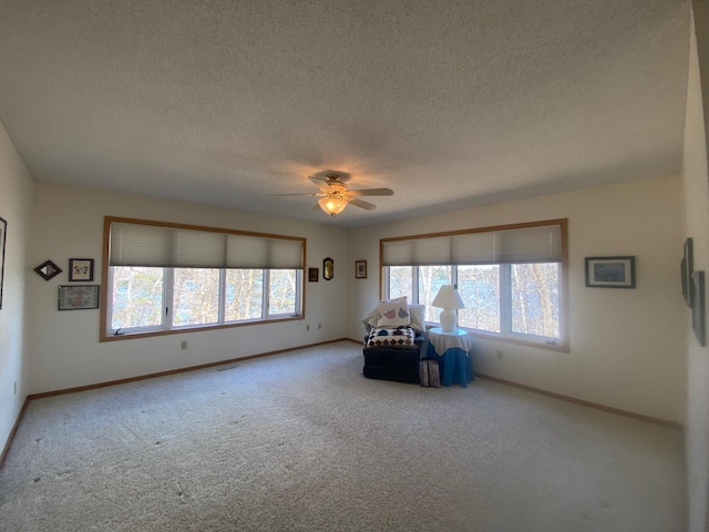 living area featuring carpet, a textured ceiling, baseboards, and ceiling fan