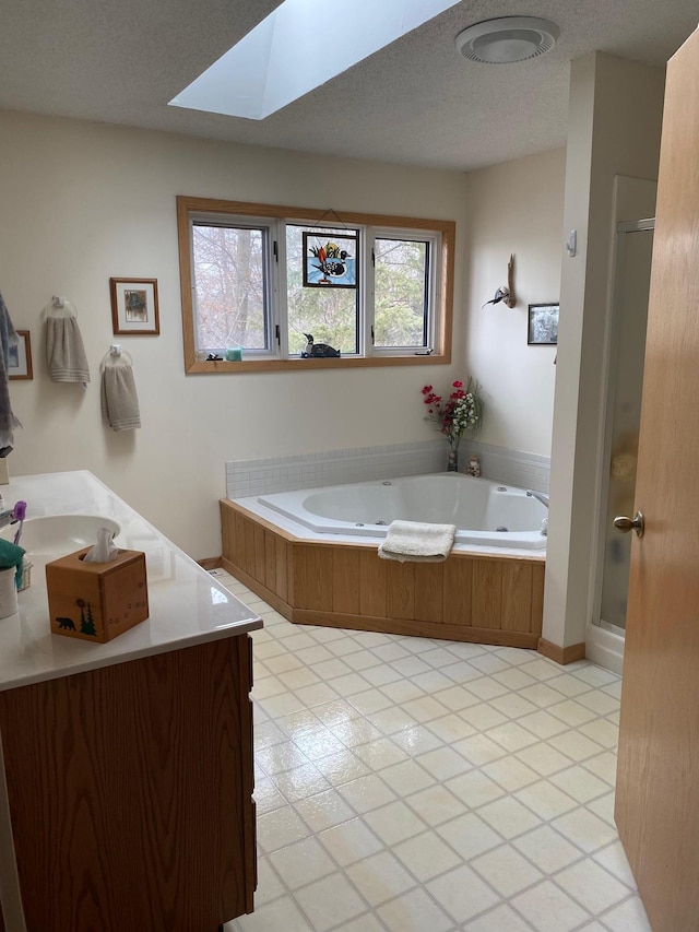 full bathroom with vanity, a skylight, a stall shower, and a tub with jets