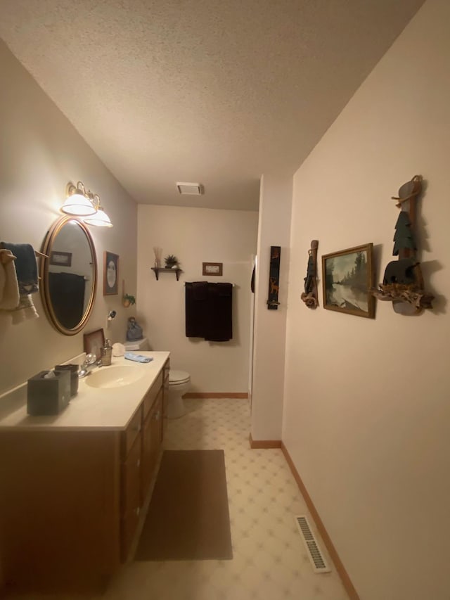 bathroom featuring tile patterned floors, visible vents, toilet, vanity, and a textured ceiling