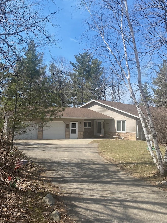 view of front of house with brick siding, an attached garage, driveway, and a front yard