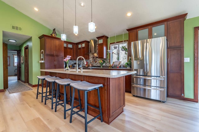918 Division St, Elbow Lake, MN 56531 - kitchen with stainless steel fridge with ice dispenser, light wood finished floors, a kitchen island with sink, vaulted ceiling, and glass insert cabinets