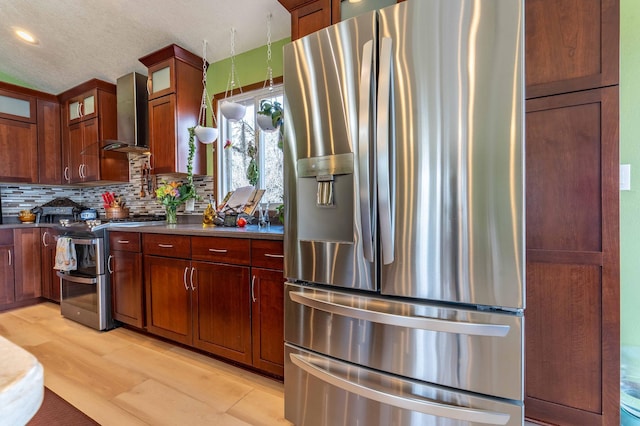 918 Division St, Elbow Lake, MN 56531 - kitchen featuring appliances with stainless steel finishes, wall chimney exhaust hood, tasteful backsplash, dark countertops, and light wood finished floors