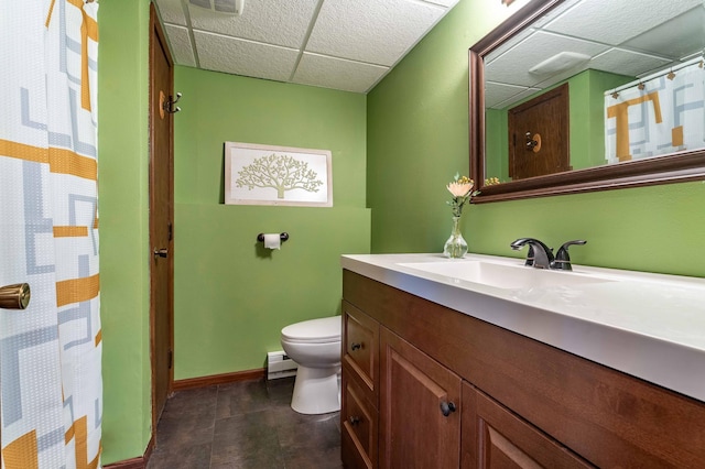 918 Division St, Elbow Lake, MN 56531 - full bathroom with a paneled ceiling, toilet, vanity, a baseboard heating unit, and baseboards
