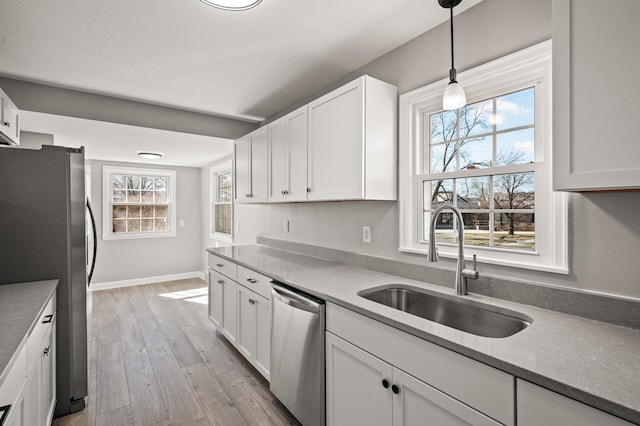 4240 Lake Road Ave, Robbinsdale, MN 55422 - kitchen featuring appliances with stainless steel finishes, light wood finished floors, a sink, and white cabinetry