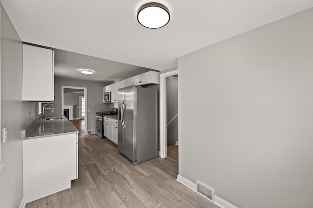 4240 Lake Road Ave, Robbinsdale, MN 55422 - kitchen with a sink, stainless steel appliances, light wood finished floors, white cabinets, and visible vents