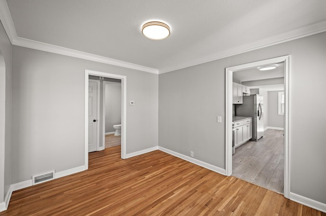 4240 Lake Road Ave, Robbinsdale, MN 55422 - unfurnished bedroom featuring light wood-type flooring, stainless steel refrigerator with ice dispenser, visible vents, and crown molding