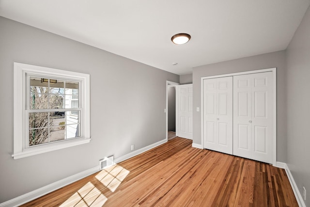 4240 Lake Road Ave, Robbinsdale, MN 55422 - unfurnished bedroom featuring a closet, light wood-style flooring, visible vents, and baseboards
