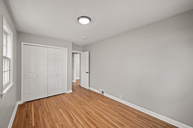 4240 Lake Road Ave, Robbinsdale, MN 55422 - unfurnished bedroom with baseboards, a closet, visible vents, and light wood-style flooring