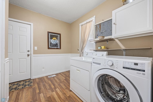 804 8th St N Unit 2, Fargo, ND 58102 - laundry room featuring separate washer and dryer, wood finished floors, cabinet space, a wainscoted wall, and a textured ceiling