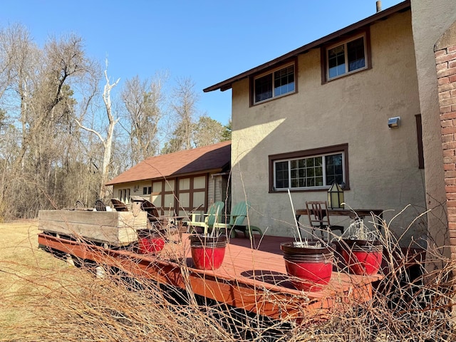 rear view of house featuring stucco siding and a deck
