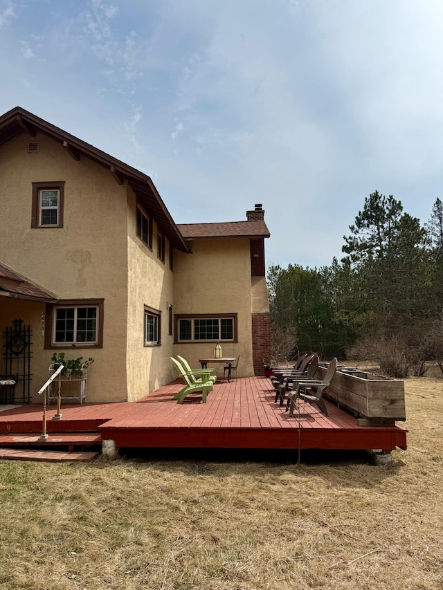 rear view of house with a deck, a yard, and stucco siding