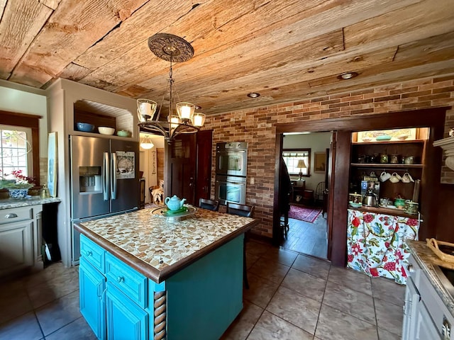 kitchen featuring brick wall, appliances with stainless steel finishes, wood ceiling, and a notable chandelier