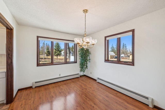 interior space with baseboard heating, an inviting chandelier, and a healthy amount of sunlight