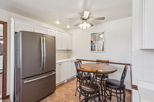 kitchen with white cabinets, decorative backsplash, ceiling fan, and freestanding refrigerator