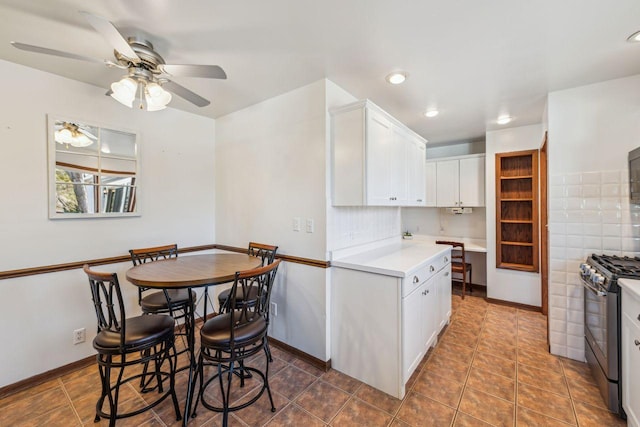 kitchen with ceiling fan, range with gas cooktop, light countertops, baseboards, and white cabinetry