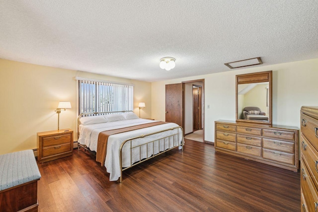 bedroom with attic access, dark wood finished floors, and a textured ceiling