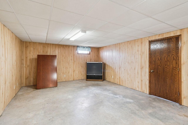 basement featuring wood walls and a paneled ceiling