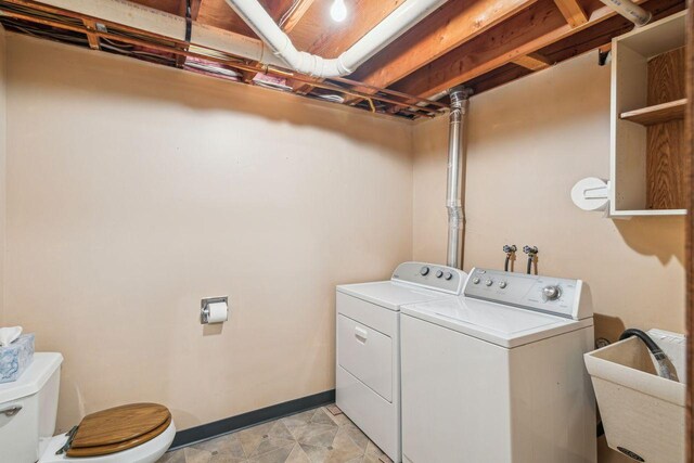 clothes washing area with baseboards, washer and dryer, and laundry area