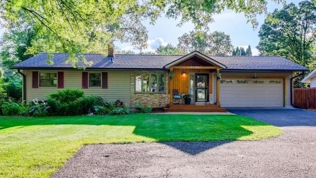 ranch-style home with an attached garage, a front lawn, driveway, and fence