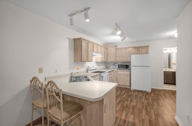 12626 43rd St NE, Saint Michael, MN 55376 - kitchen featuring white appliances, under cabinet range hood, a sink, light countertops, and a peninsula