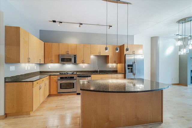 401 2nd St N Unit 220, Minneapolis, MN 55401 - kitchen featuring light wood finished floors, a sink, dark stone countertops, a kitchen island, and appliances with stainless steel finishes
