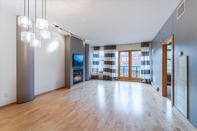 401 2nd St N Unit 220, Minneapolis, MN 55401 - unfurnished living room featuring french doors, visible vents, a glass covered fireplace, wood finished floors, and a baseboard radiator