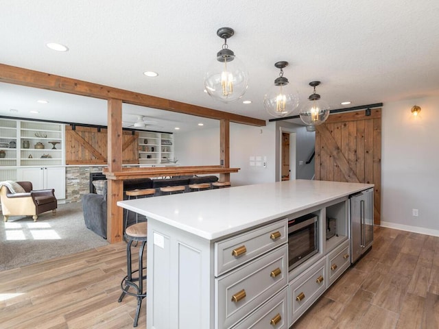 11460 Eagle Creek Ln, Rogers, MN 55374 - kitchen with stainless steel microwave, a breakfast bar, light wood finished floors, light countertops, and recessed lighting