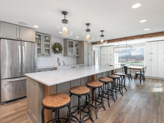 11460 Eagle Creek Ln, Rogers, MN 55374 - kitchen featuring freestanding refrigerator, light wood-style flooring, gray cabinets, decorative backsplash, and light countertops