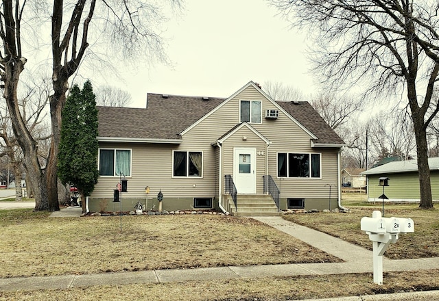 bungalow-style house featuring a shingled roof and a front yard